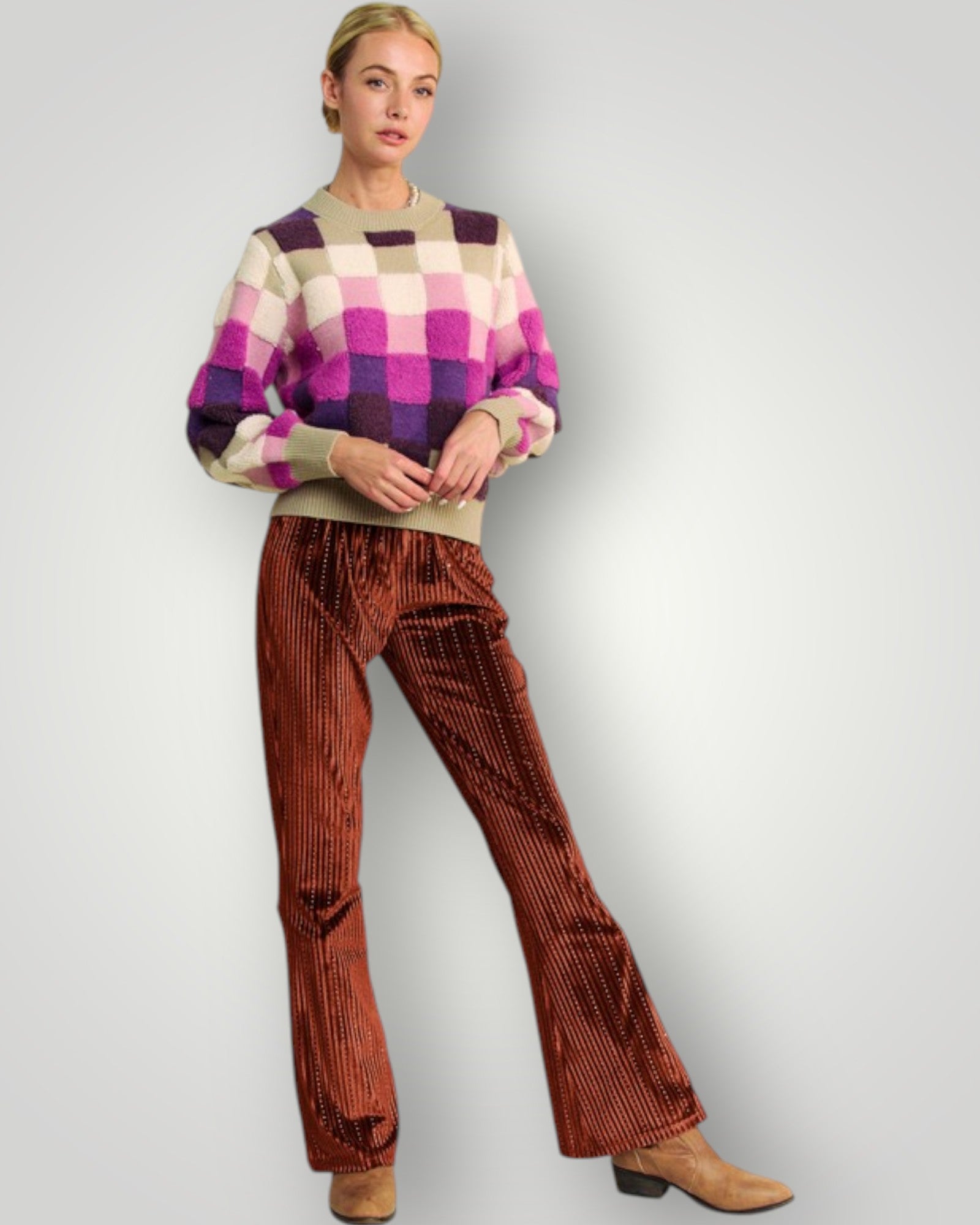 Woman wearing a checkered sweater and corduroy pants on a plain background
