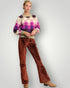 Woman wearing a checkered sweater and corduroy pants on a plain background