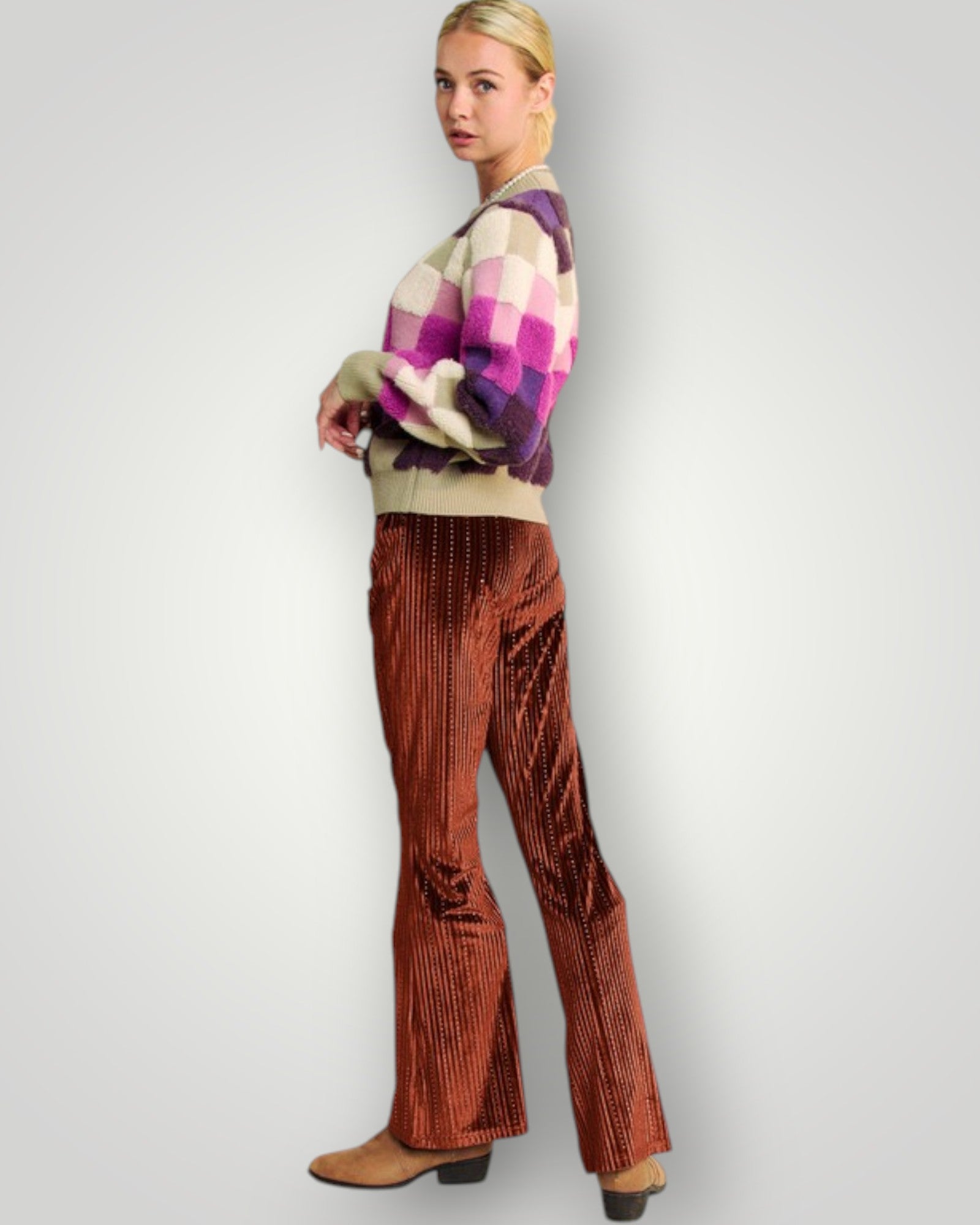 Woman wearing a plaid sweater and brown flared pants on a plain background
