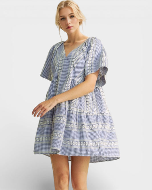 Woman wearing a blue and white patterned dress on a light gray background