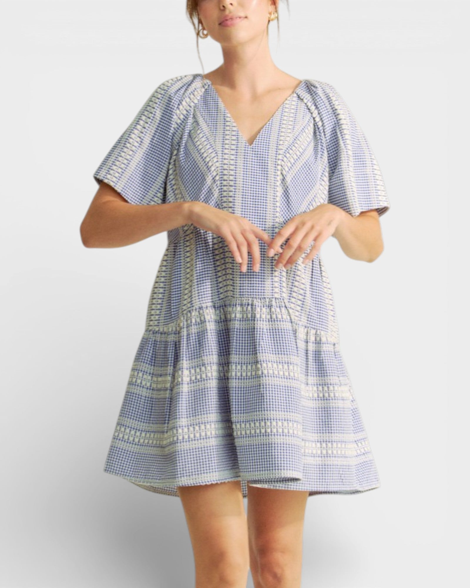 Woman wearing a blue and white patterned dress on a plain background