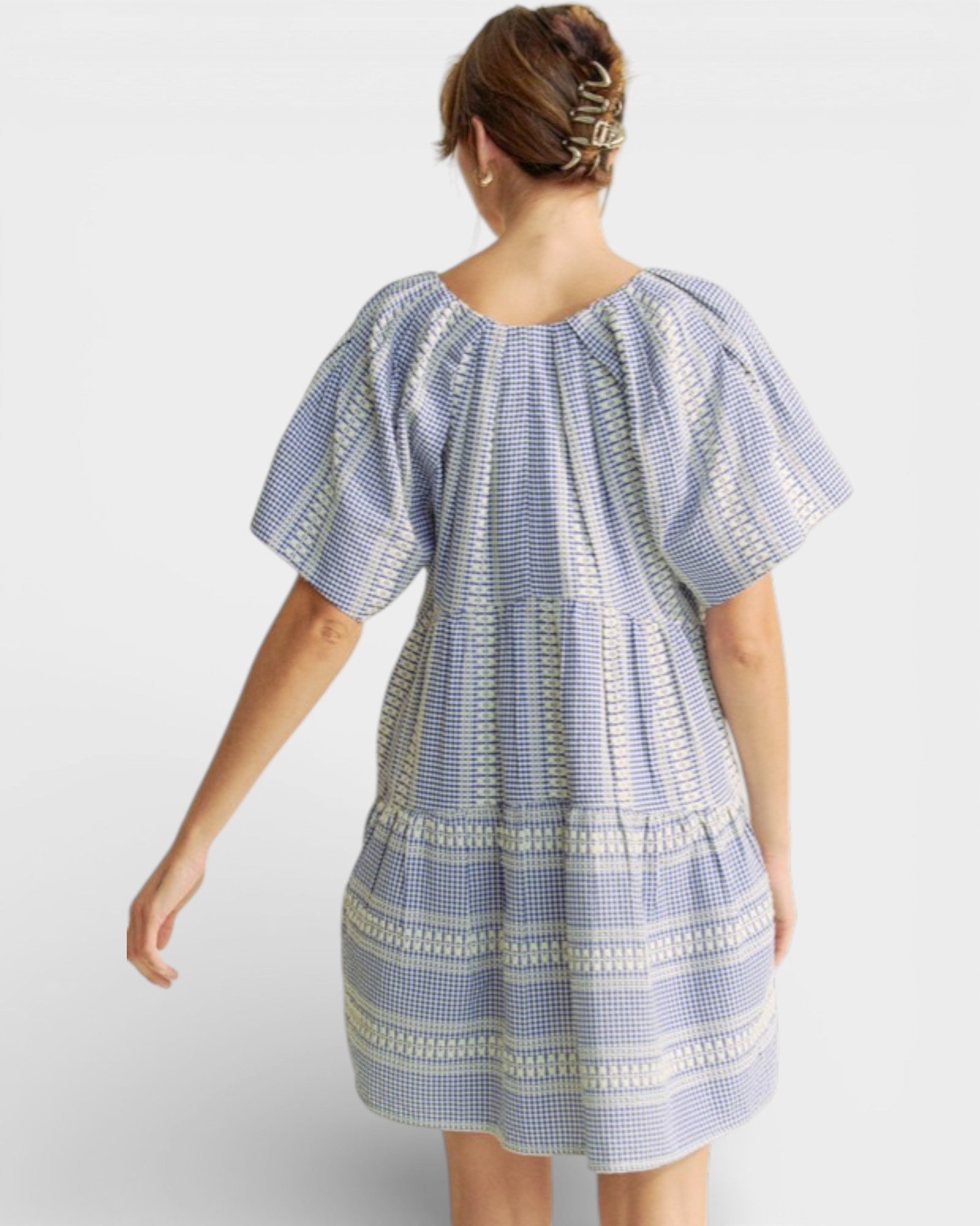 Woman wearing a blue and white patterned dress on a white background