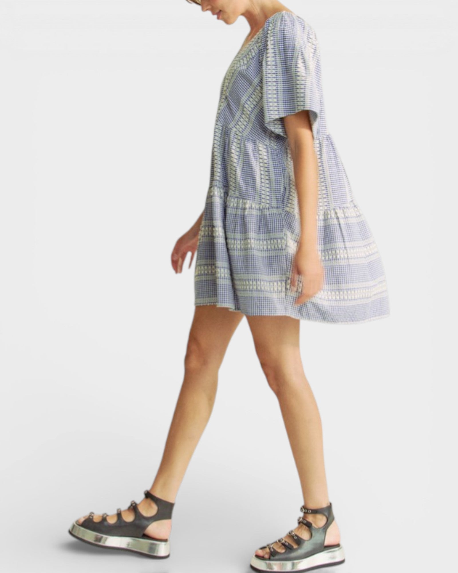 Woman wearing a patterned dress and sandals on a white background
