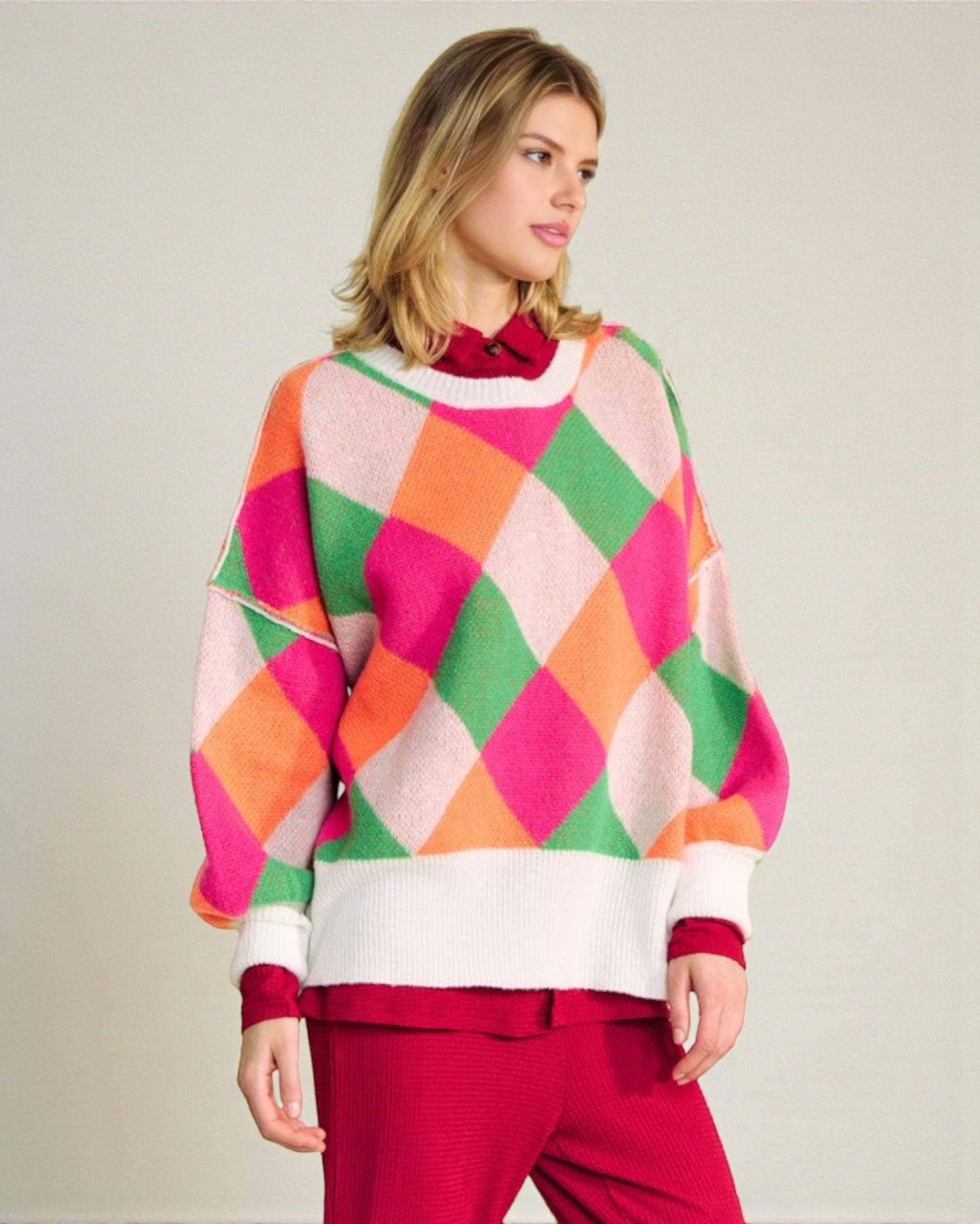 Woman wearing a colorful argyle sweater with a plain background