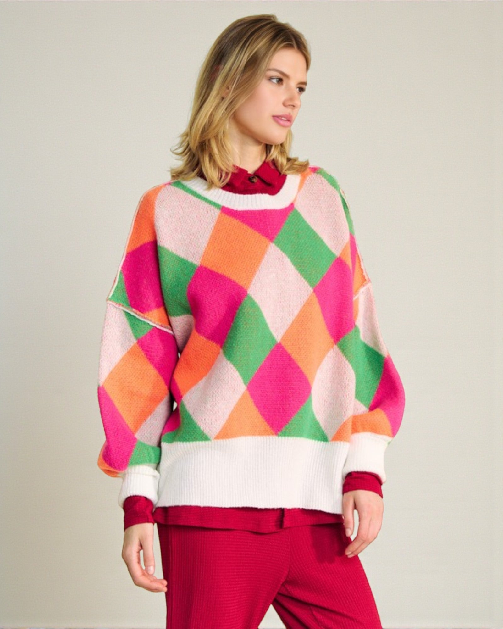 Woman wearing a colorful argyle sweater with a plain background