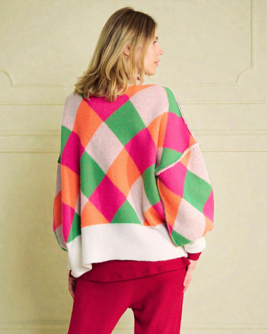 Person wearing a colorful diamond patterned sweater against a plain background