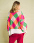 Person wearing a colorful diamond patterned sweater against a plain background