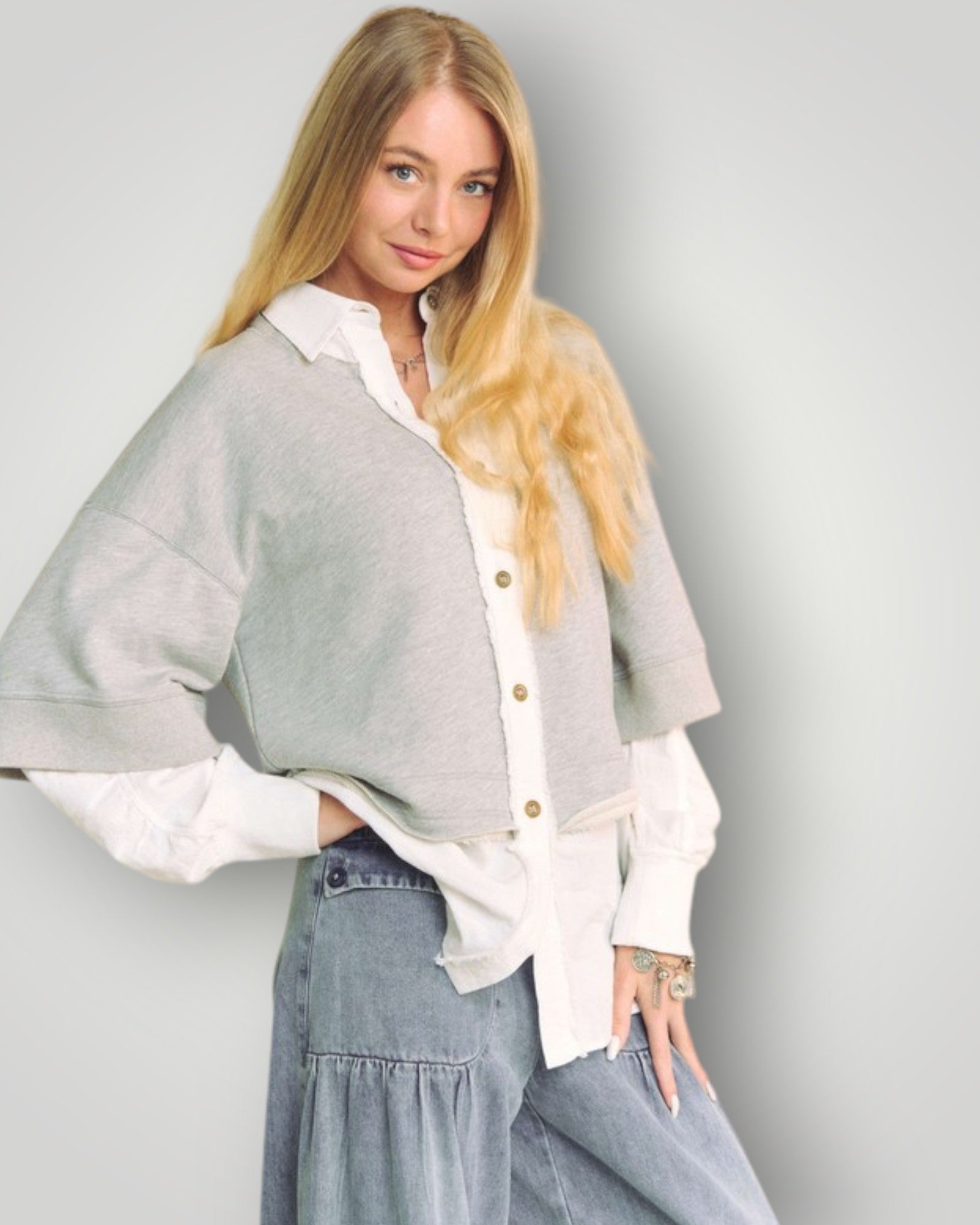 Woman wearing a gray cardigan over a white shirt with a plain background