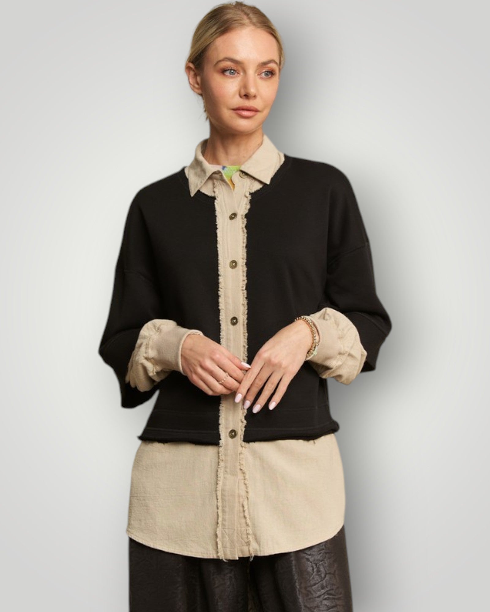 Woman wearing a black and beige two-tone shirt against a plain background