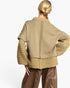 A woman shown from the back wearing a cropped knit cardigan with ribbed trim and brown wide-leg pants, photographed against a clean white studio background.