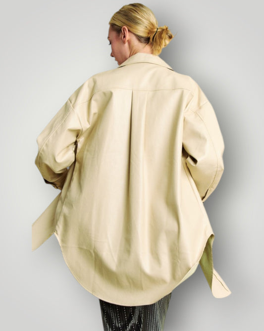 Person wearing a beige oversized shirt against a plain background