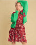 Woman wearing a red floral dress with a green cardigan on a beige background