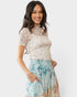 Woman wearing a floral top and skirt on a white background