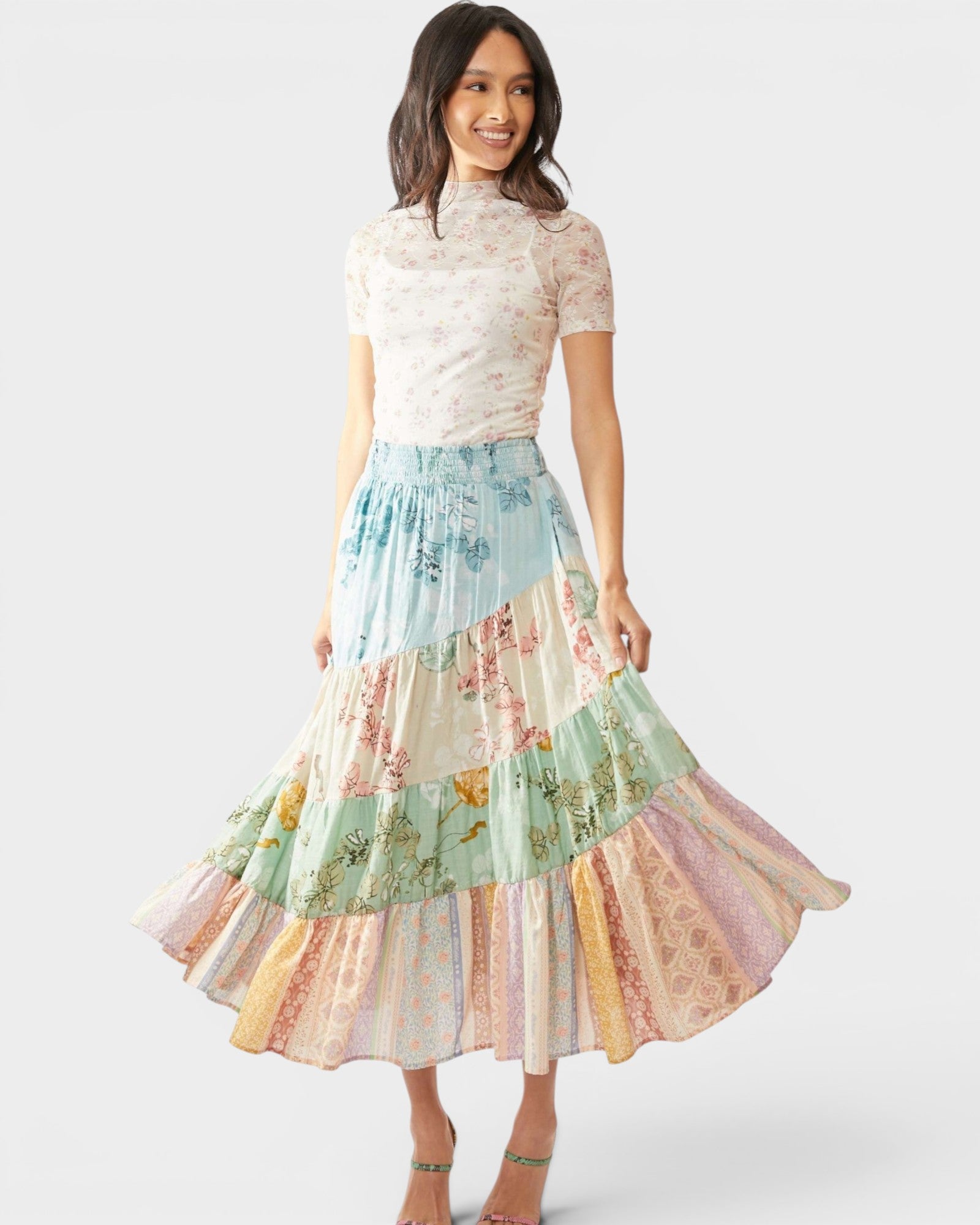 Woman wearing a pastel tiered skirt with a white top on a white background