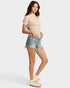 Woman wearing a lace top and denim shorts on a plain background