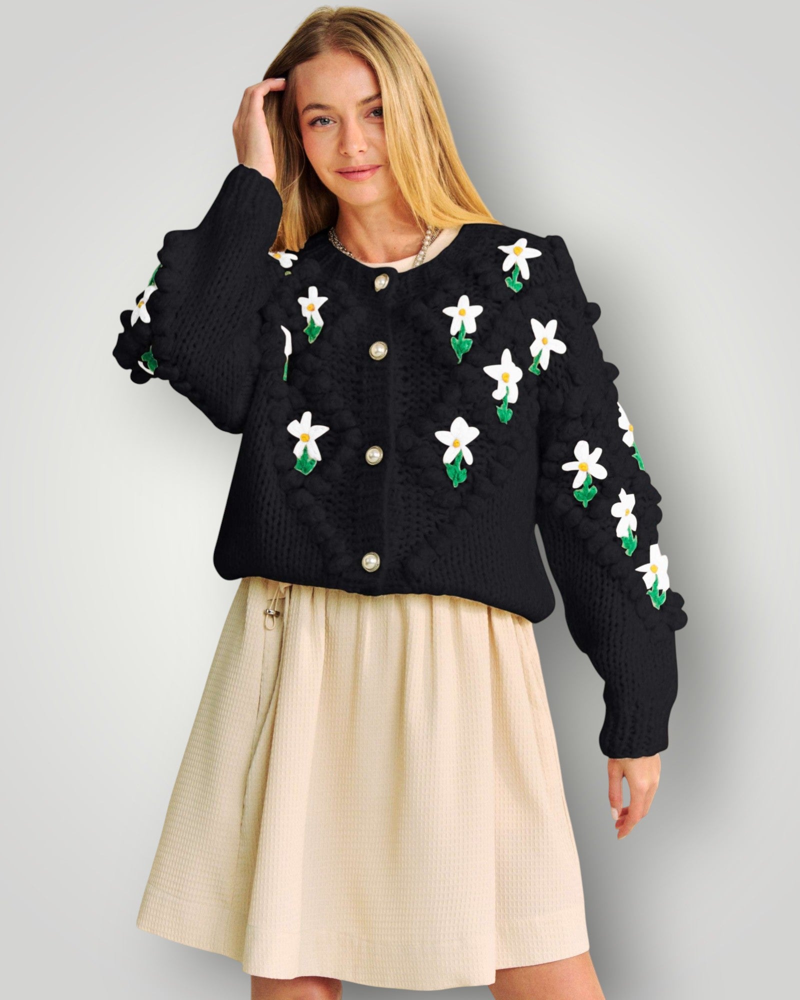 Woman wearing a black sweater with floral patterns on a gray background