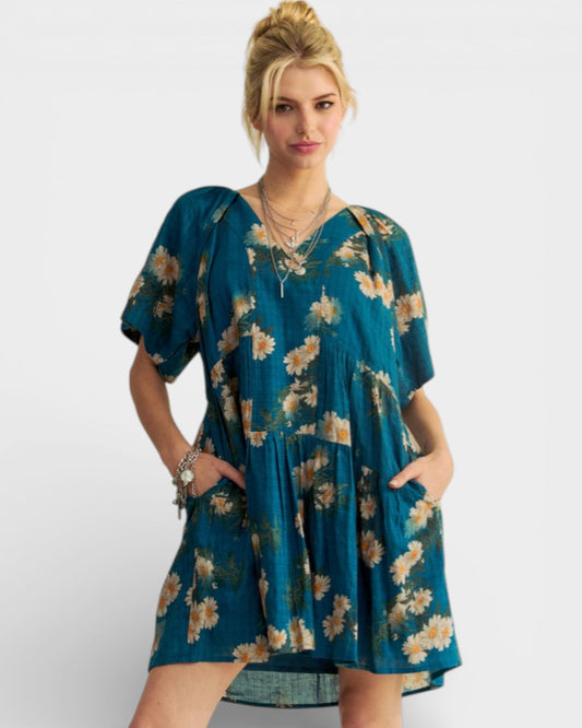 Woman wearing a teal floral dress on a white background