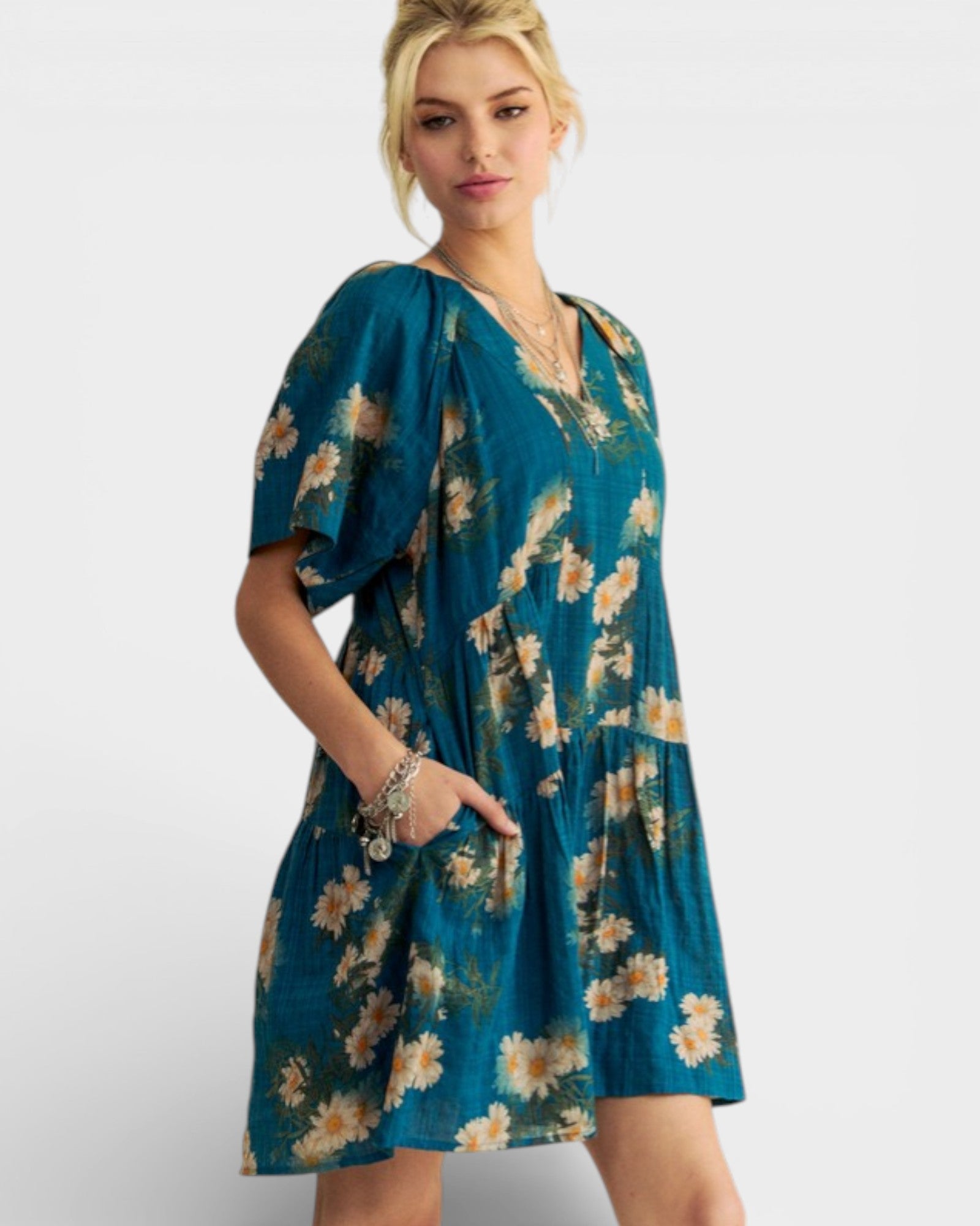 Woman wearing a teal floral dress on a white background