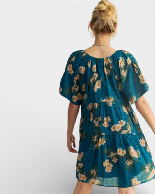 Woman wearing a teal floral dress on a white background