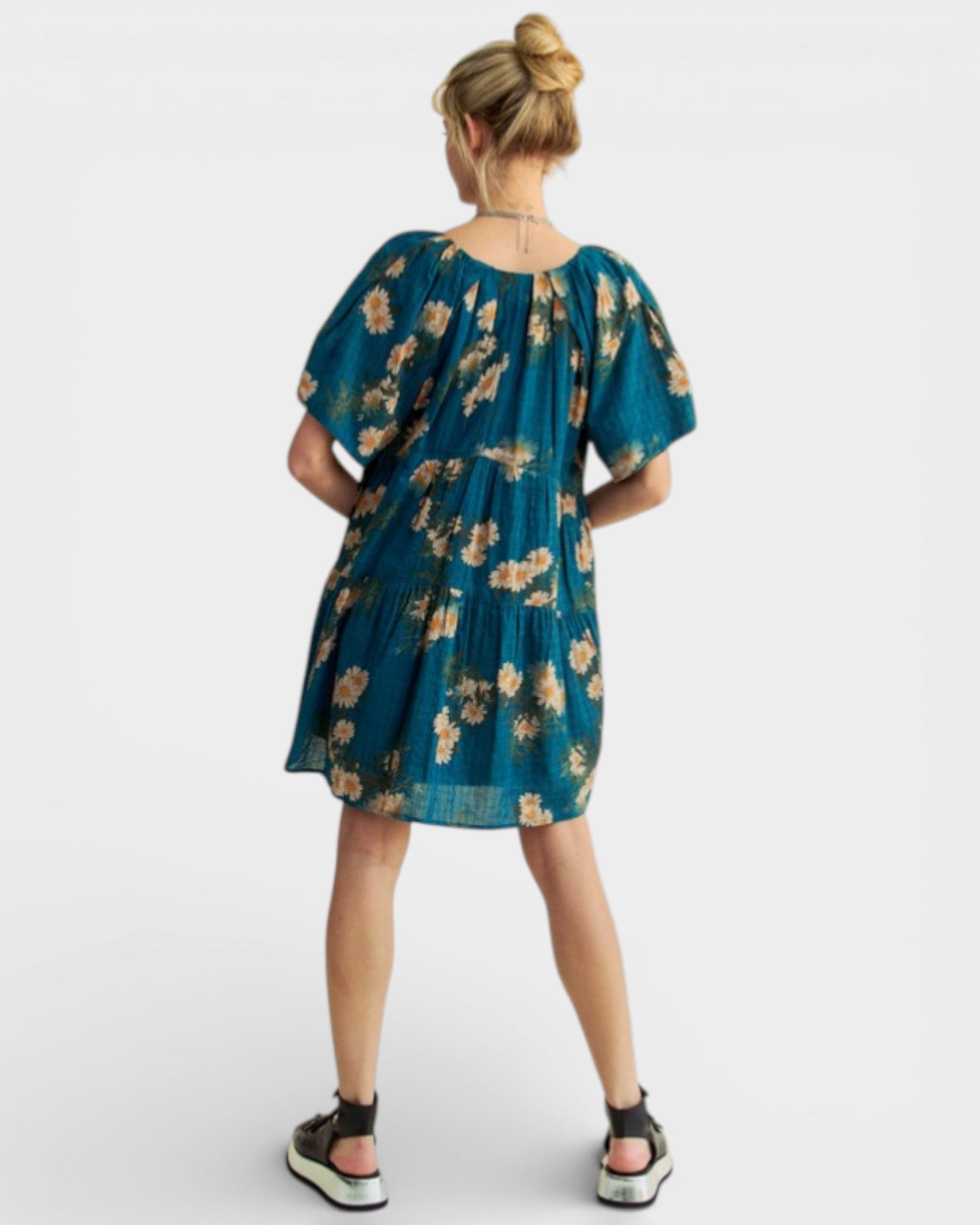 Woman wearing a teal floral dress on a white background