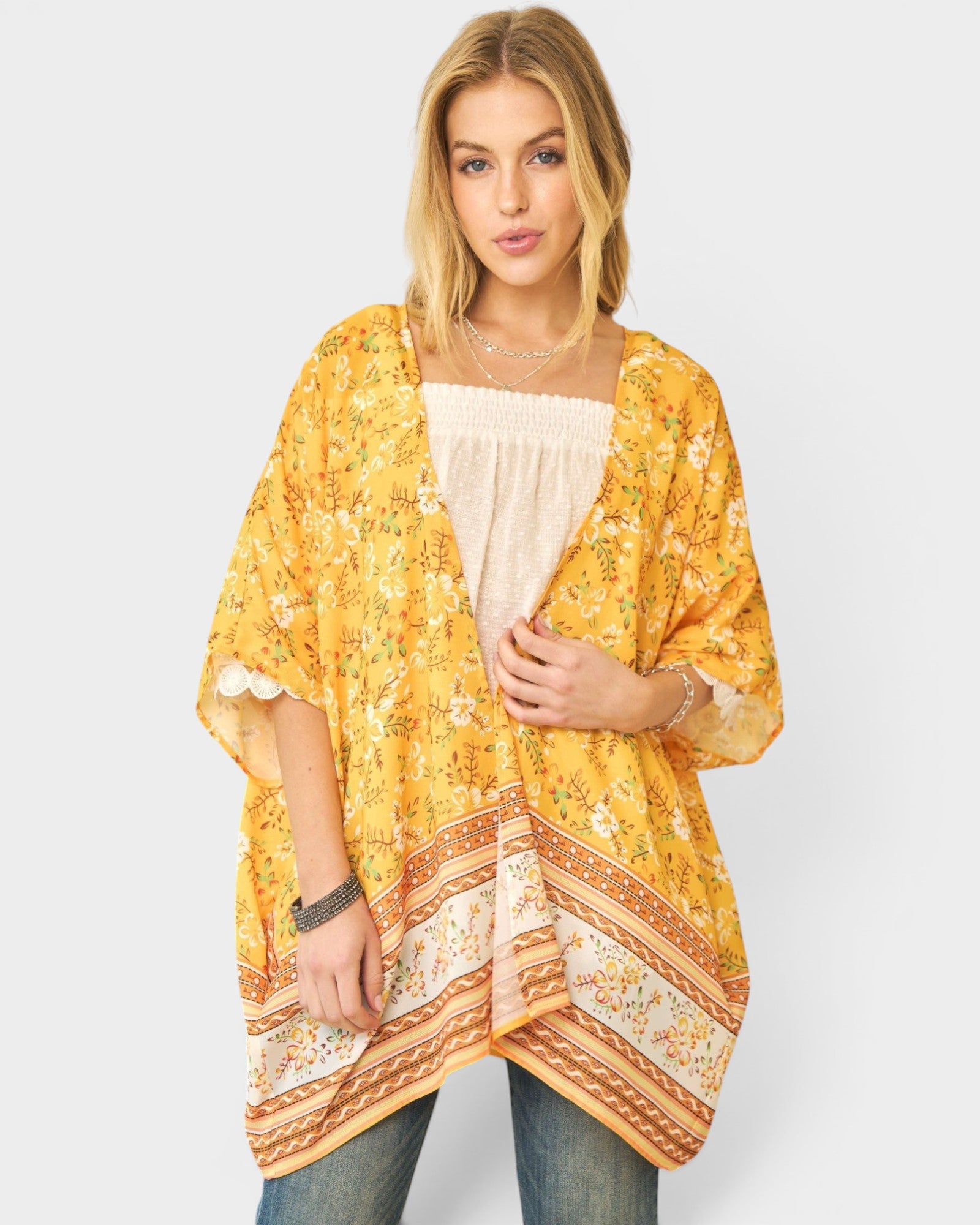 Woman wearing a yellow floral kimono-style top on a white background