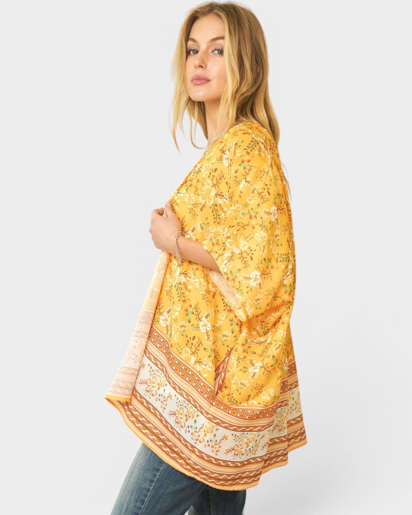 Woman wearing a yellow floral kimono-style top on a white background