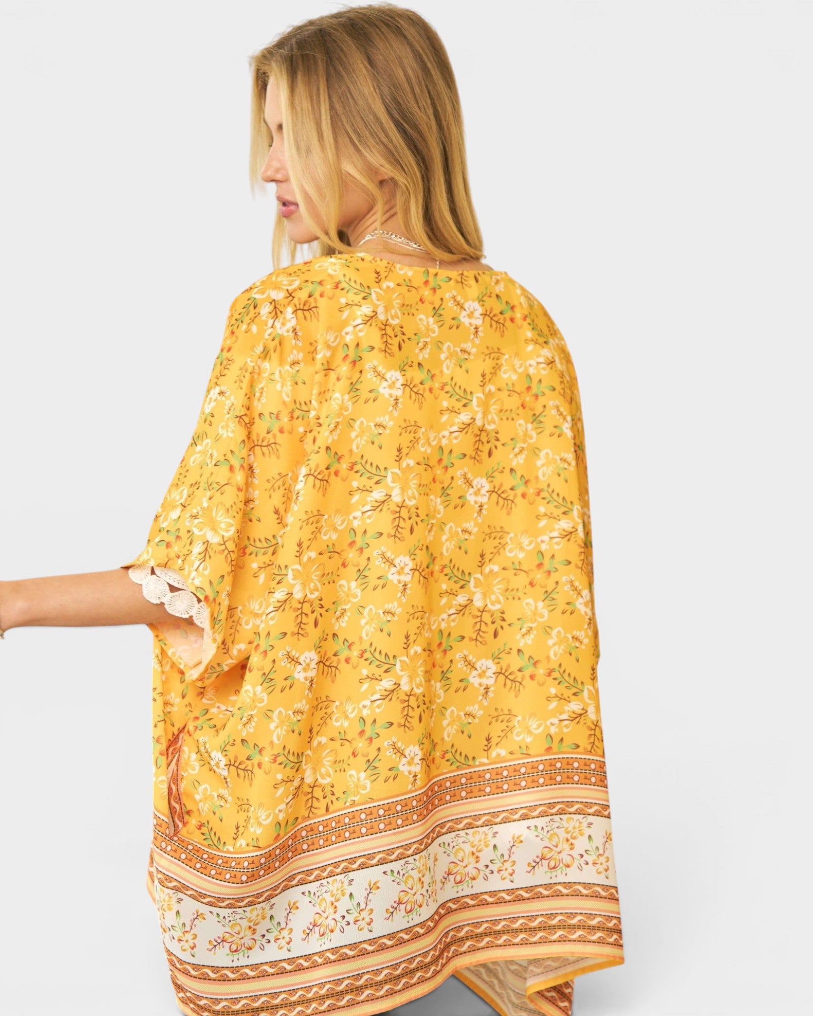 Woman wearing a yellow floral patterned scarf on a plain background