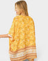 Woman wearing a yellow floral patterned scarf on a plain background