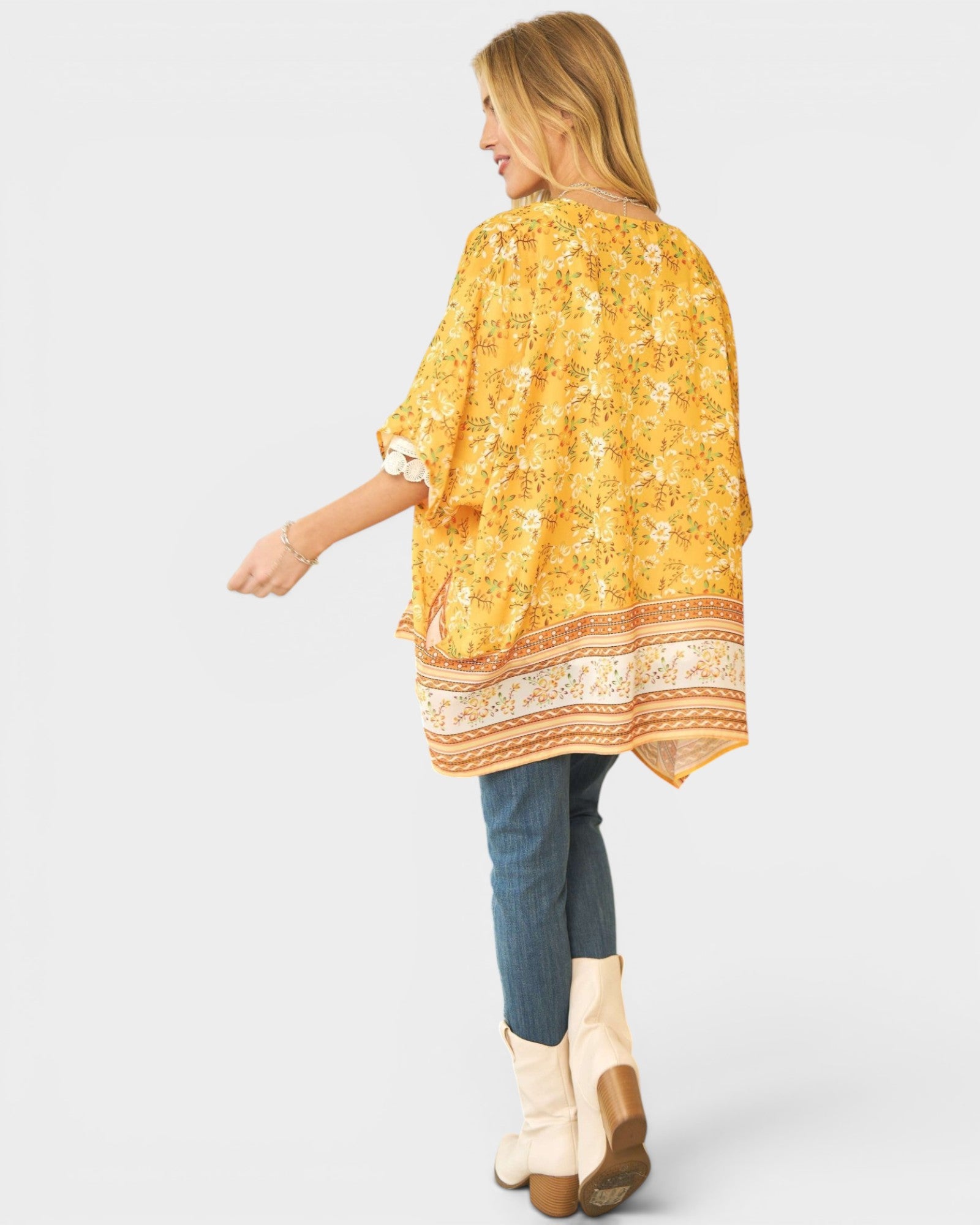 Woman wearing a yellow floral kimono-style top on a white background
