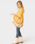 Woman wearing a yellow patterned kimono over a white top and blue jeans, standing against a white background.