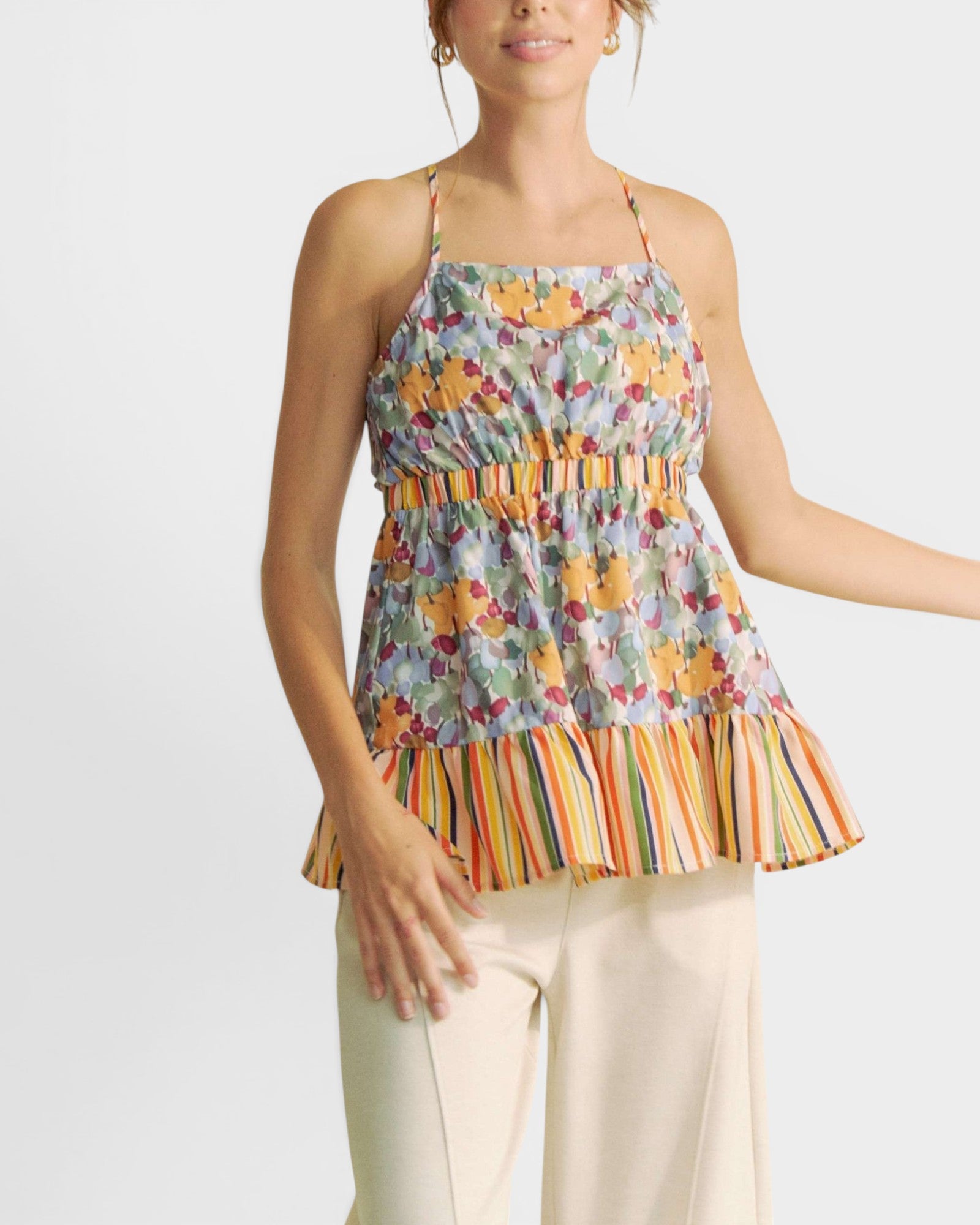 Woman wearing a colorful floral and striped top on a white background