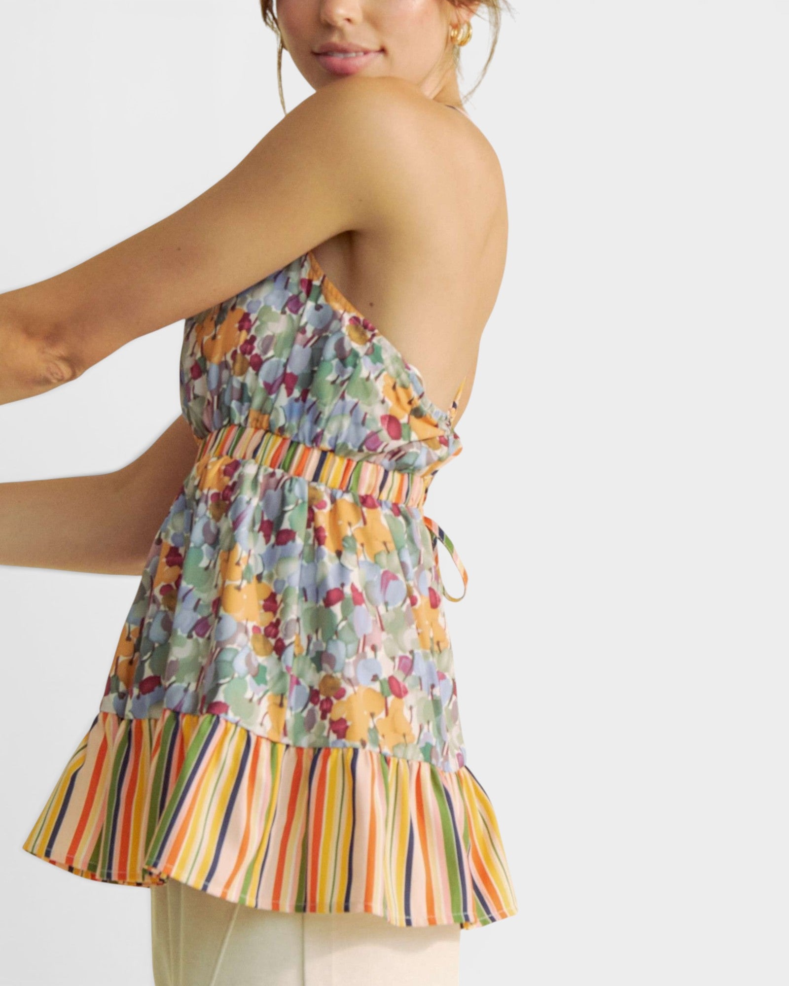 Woman wearing a colorful floral and striped dress on a white background