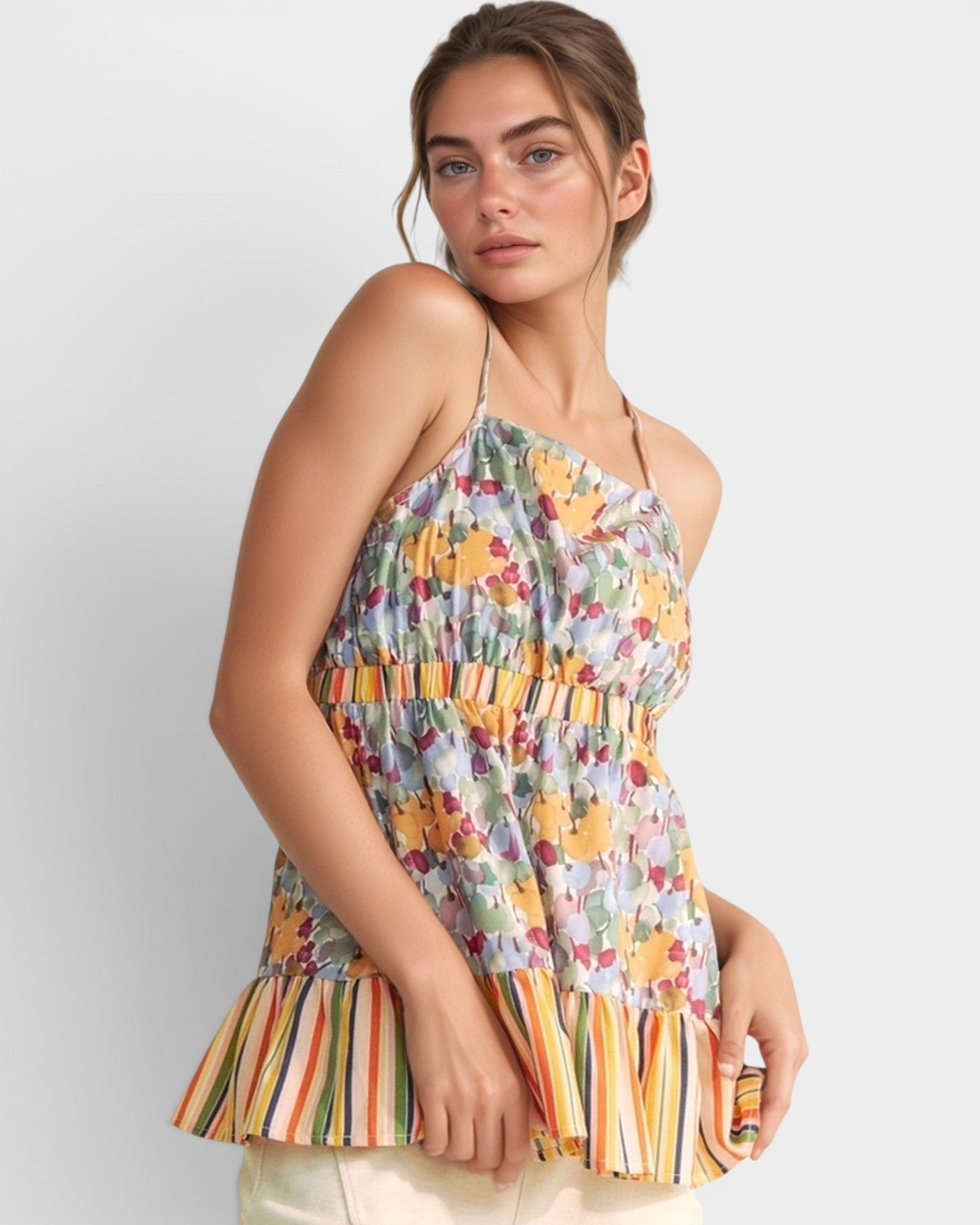 Woman wearing a colorful floral and striped top against a white background
