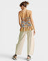 Woman wearing a colorful top and beige pants on a white background