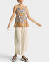 Woman wearing a colorful floral top and beige pants on a white background