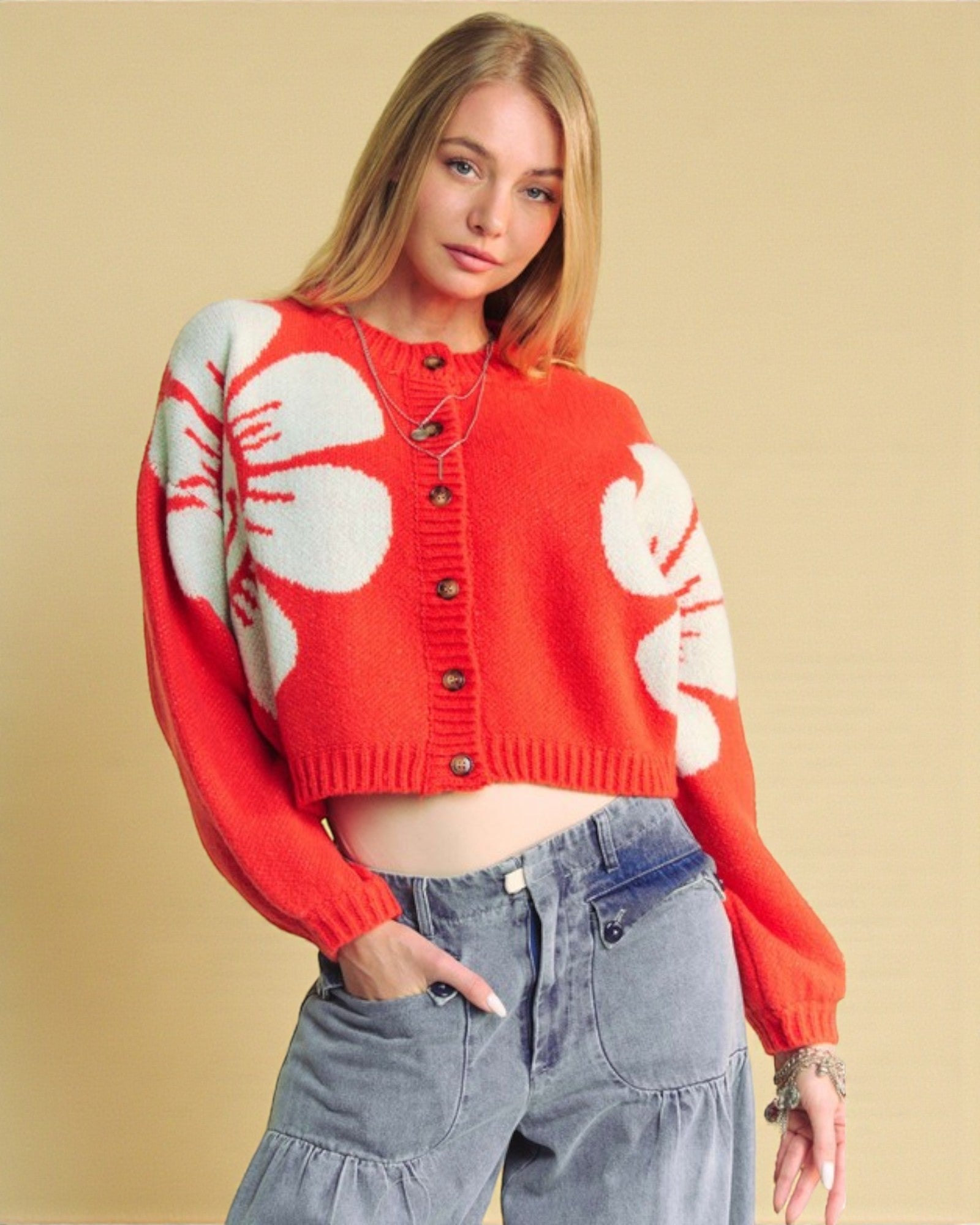Woman wearing a red sweater with white floral patterns on a beige background