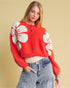 Woman wearing a red sweater with white floral patterns on a beige background