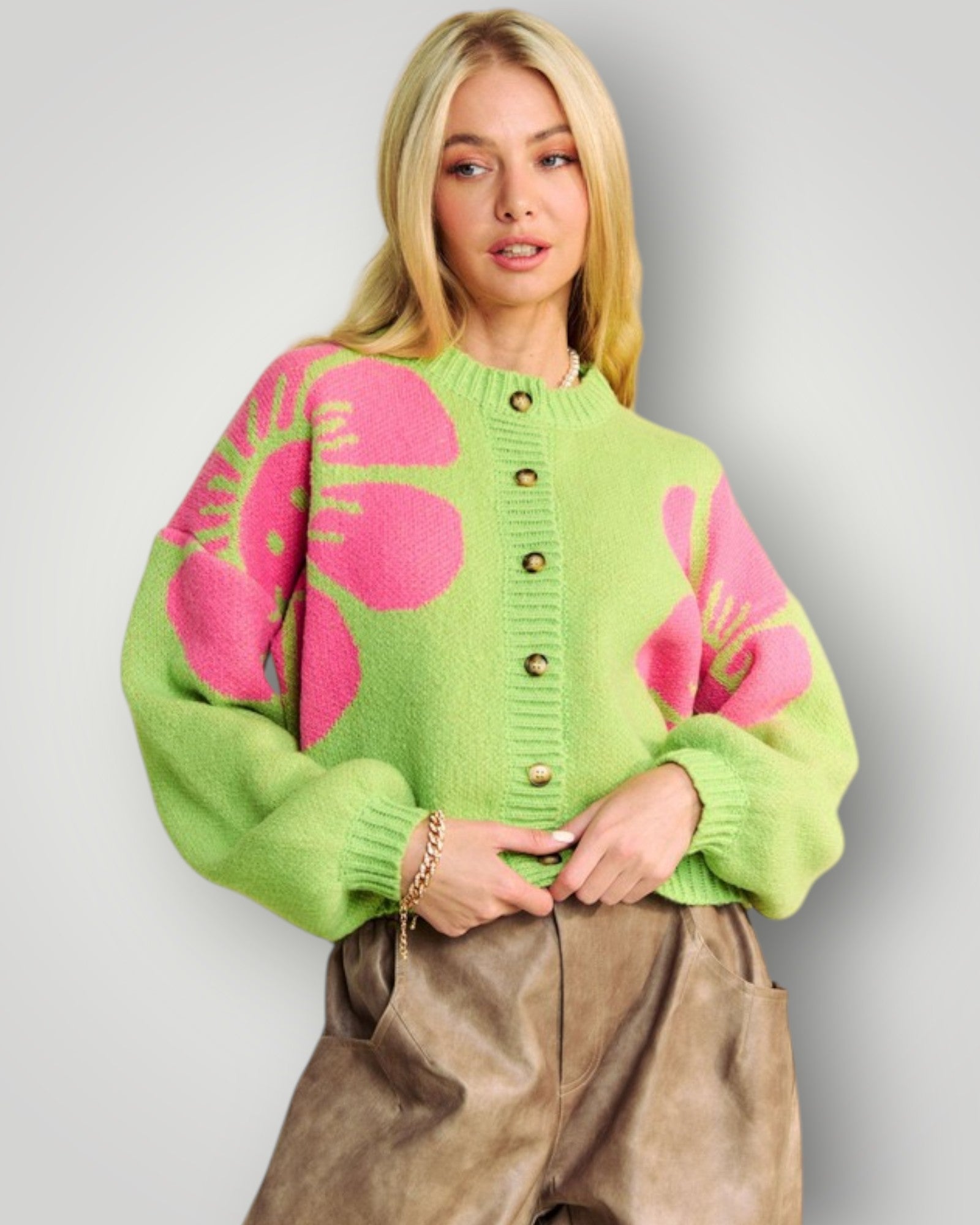 Woman wearing a green sweater with pink floral patterns against a plain background