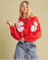 Person wearing a red sweater with white paw prints against a beige background
