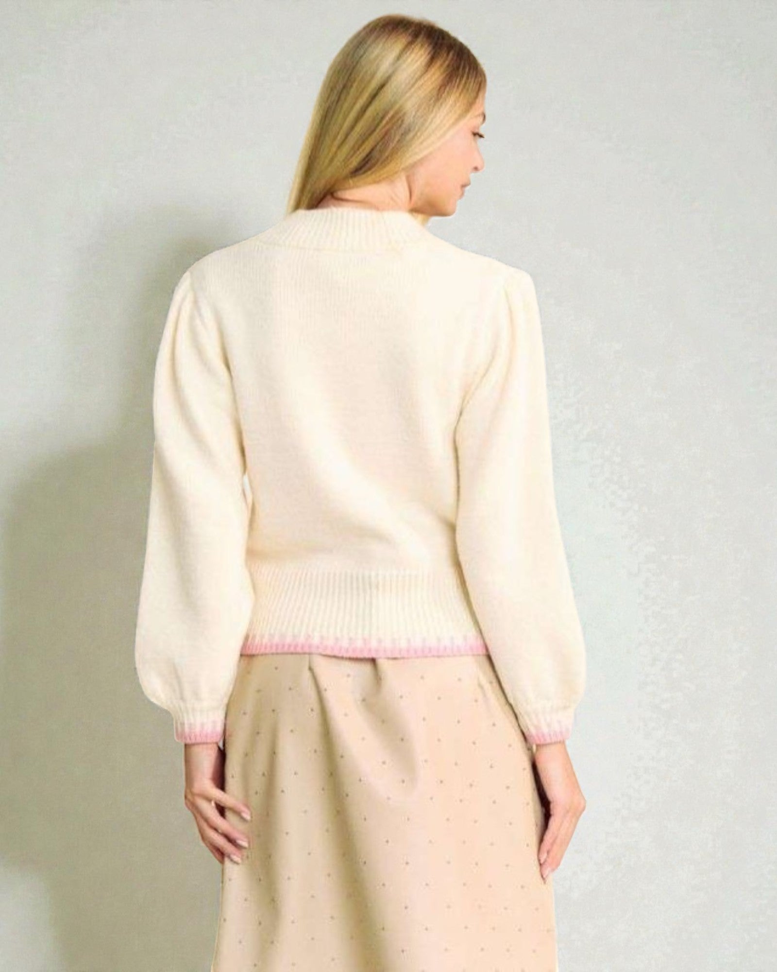 Woman wearing a light-colored cardigan and skirt against a plain background
