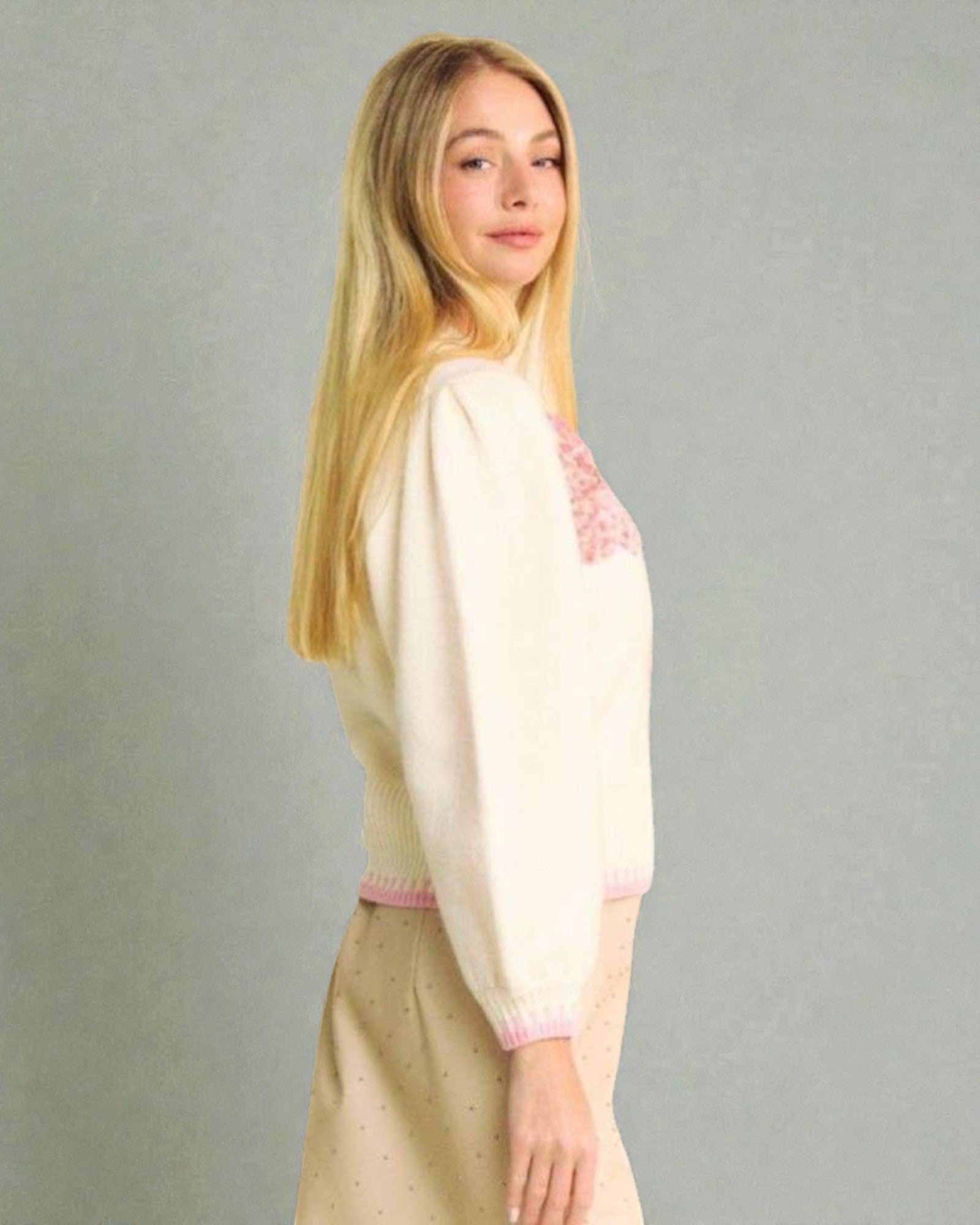 Woman wearing a light-colored outfit with pink accents on a plain background