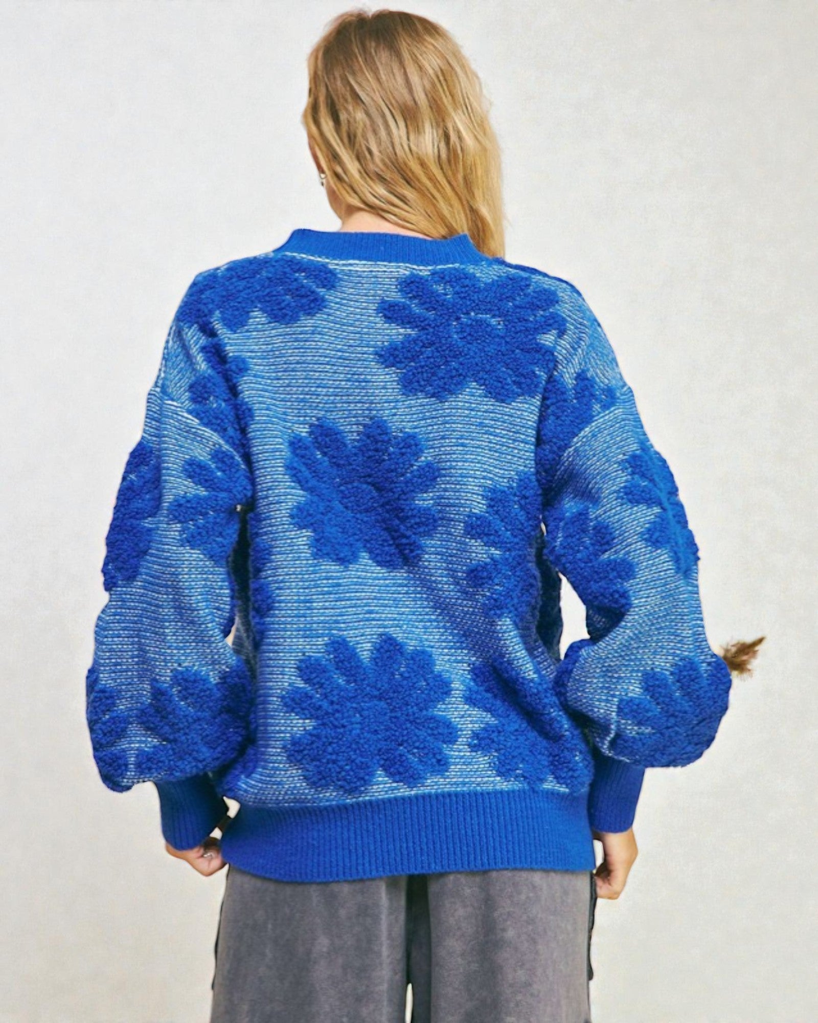 Person wearing a blue floral-patterned sweater on a plain background