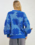 Person wearing a blue floral-patterned sweater on a plain background