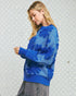 Woman wearing a blue patterned sweater against a polka dot background