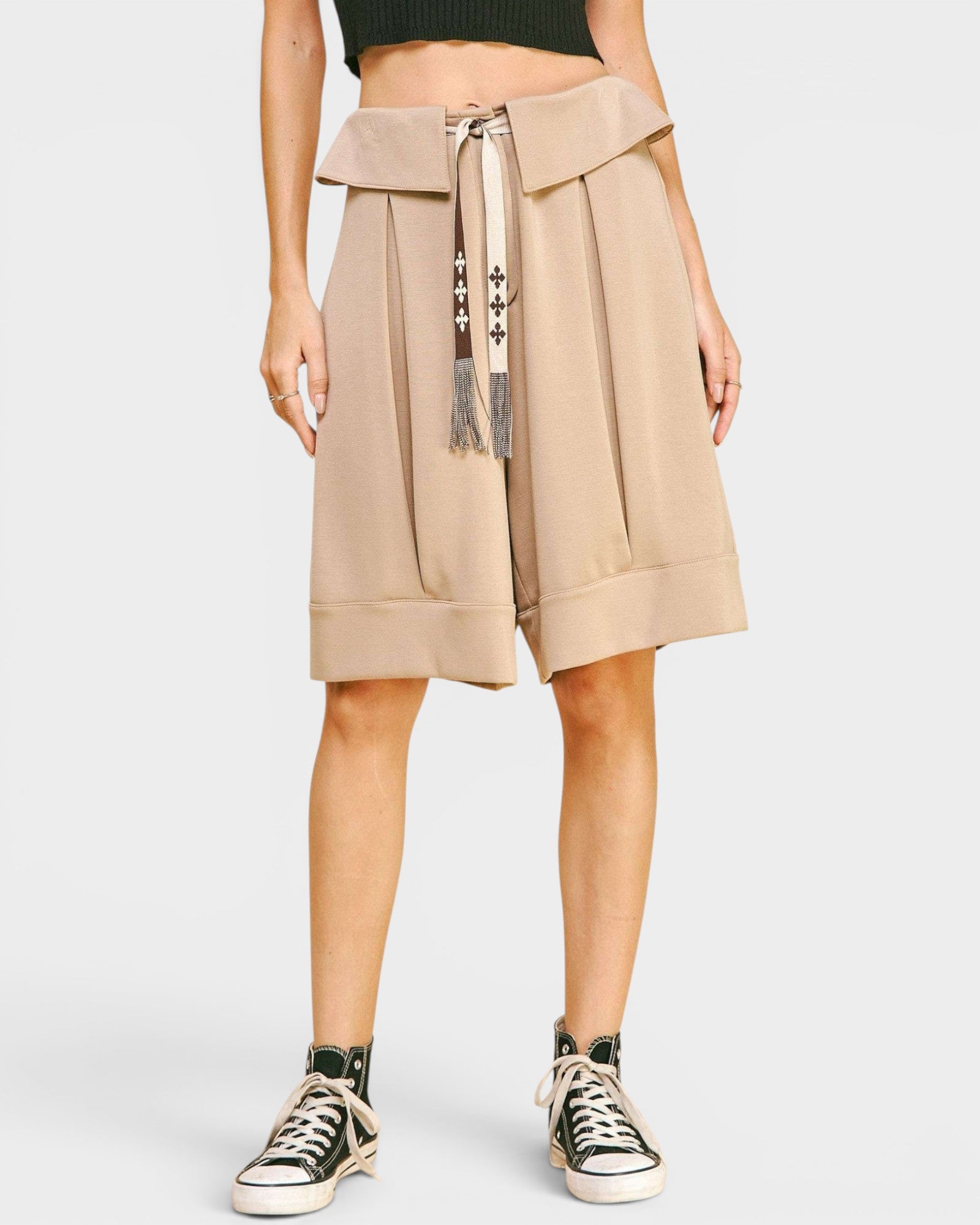 Person wearing a beige skirt with a belt on a white background