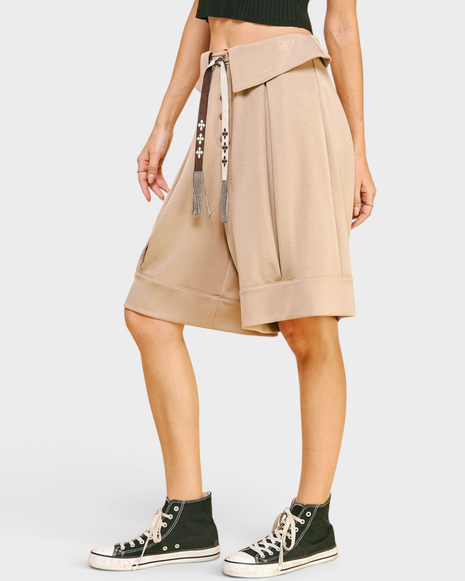 Beige skirt with a belt and black high-top sneakers on a white background