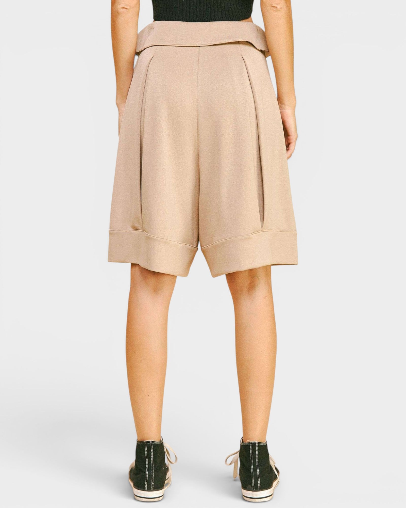 Beige shorts worn by a person on a white background