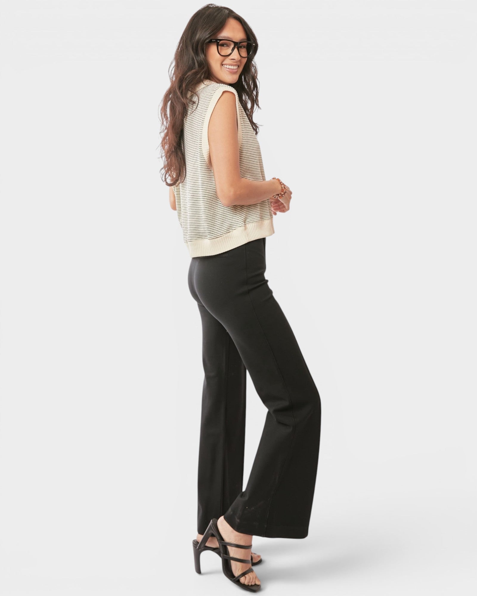 Woman wearing a sleeveless top and black pants on a white background