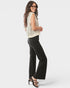 Woman wearing a sleeveless top and black pants on a white background