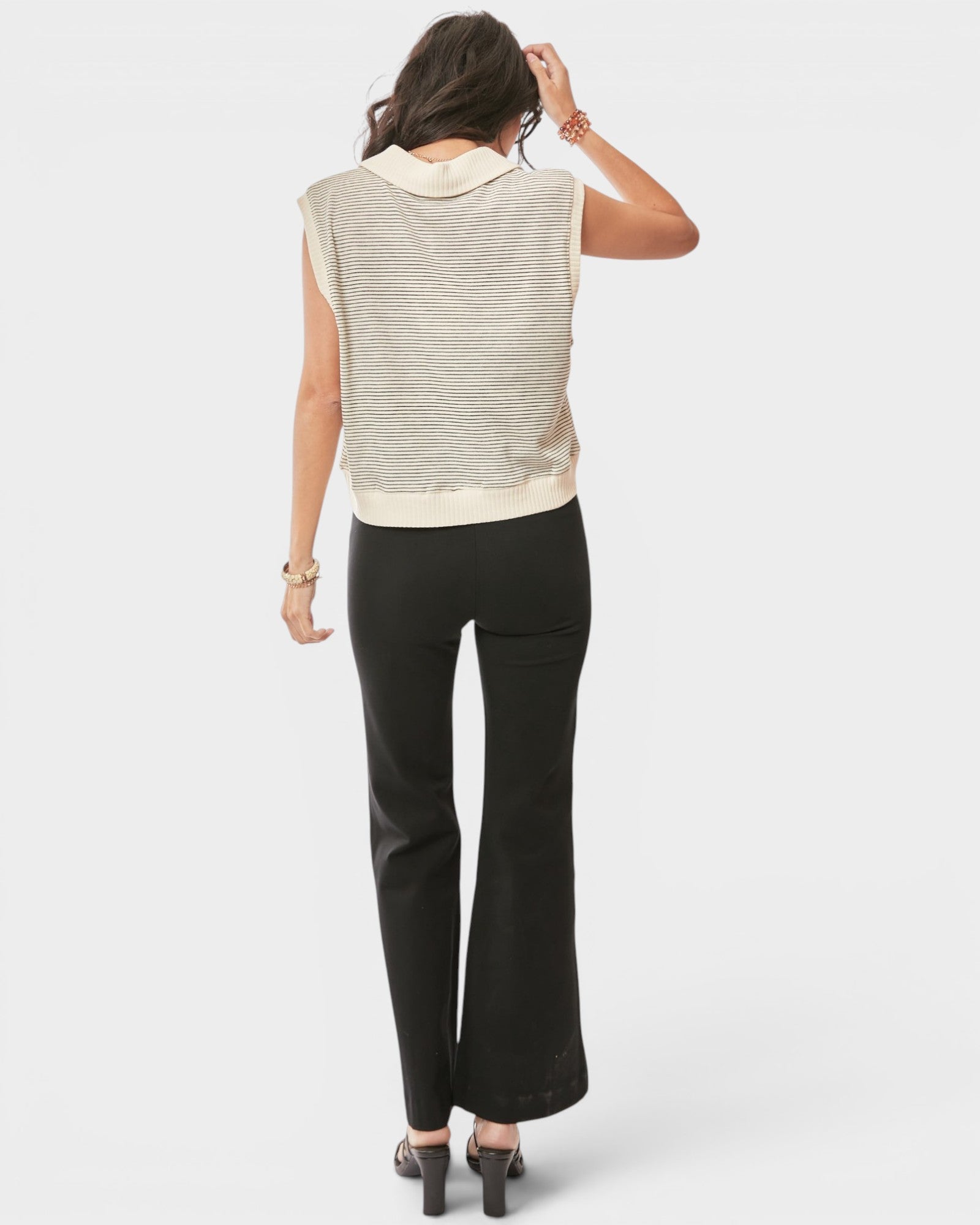 Woman wearing a sleeveless striped top and black pants on a white background